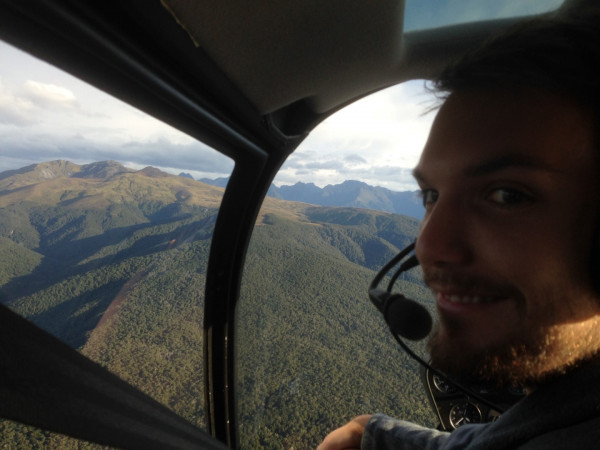 a man in a helicopter with mountains in the background