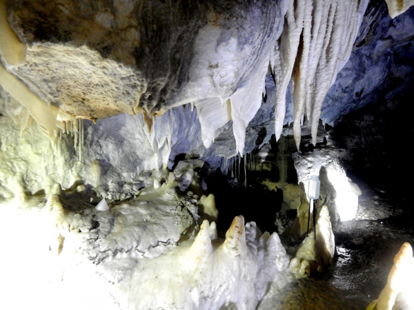 a cave with dripstones and a propped-up plastic bottle