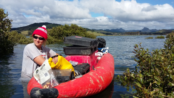 a researcher wading with a canoe in a bay with mangroves